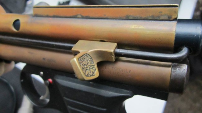 Brass thumb rest cast by Derrick Obatake. This thumb rest is used to keep the pump handle and bolt from opening unintentionally.