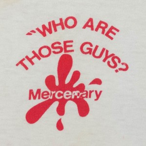 Close up crop on back side of "Who Are Those Guys?" shirt logo.