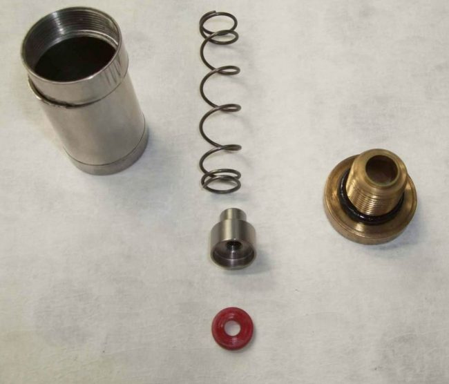 Valve sleeve on left. Crack in casing is visible. Valve spring, cup, seal and valve retaining screw also pictured. Photo courtesy Paul Cross.